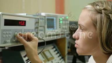 年轻的女工程师学生在实验室用电气仪器工作。 她小心翼翼地<strong>转动</strong>车轮<strong>时钟</strong>